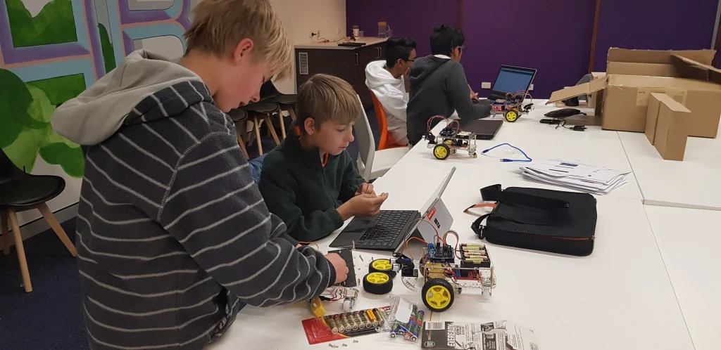 A child confidently coding on a laptop, engaged in a hands-on robotics and programming lesson.